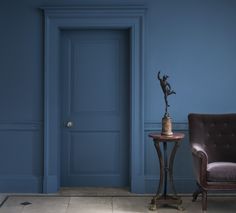 a blue room with a chair, table and door