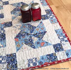 two jars of jam sit on top of a quilt