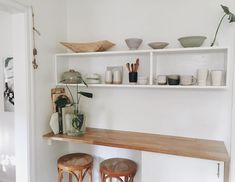 two wooden stools sitting on top of a shelf in a room with white walls