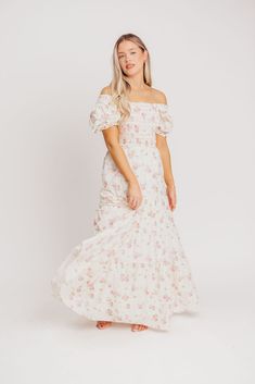 If you're looking ahead to blooming flowers and sunshine, you need this beautiful dress to help herald in springtime! This gem is crafted from a charming, 100% cotton floral print, and features a smocked bodice with sleeves that can be worn on or off the shoulders. It's a must-have for baby showers, gender reveals, or christenings! The Harper is sure to sell out, so don't wait to snag yours! FIT: Runs true to size. The bodice is stretchy and smocked, but the rest of the dress does not have stret Pink Cottagecore Dress For Brunch, Feminine Maxi Dress For Garden Party In Spring, Feminine Spring Maxi Dress For Garden Party, Feminine Floral Embroidered Maxi Dress For Garden Party, Feminine Maxi Dress With Floral Embroidery For Garden Party, Flowy Cottagecore Dress For Garden Party, Cottagecore Flowy Dress For Garden Party, White Feminine Floral Dress For Garden Party, Flowy Feminine Floral Embroidered Maxi Dress