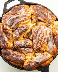 a pan filled with cinnamon rolls covered in icing on top of a white table