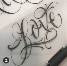 the word love written in cursive writing on a sheet of paper with a pen