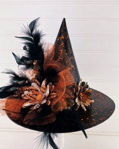 an orange and black witches hat with feathers