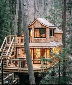 a wooden house in the woods with stairs leading up to it's second story