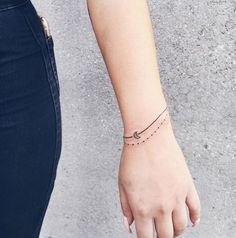 a woman's arm with a small bracelet on it and a tiny heart tattoo