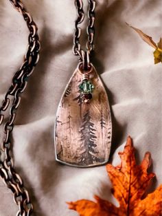 This lovely copper necklace was made from a copper sheet and pressed in a pancake die to cut our tour the shield shap. I rolled the copper sheet in a rolling mill with a pretty tree pattern. I put a black patina on to bring out the pattern in the impression. I added a pretty green crystal that hang down with a copper head pin. I attached copper jump rings and hung it from a 24 inch copper necklace. The pendant is 5/8 inches wide and 1 1/5 inches in length.  This necklace would be a perfect gift Copper Necklace Handmade, Bohemian Engraved Copper Necklaces, Brown Stamped Copper Jewelry, Hammered Bronze Copper Necklace, Bronze Hammered Copper Necklace, Copper Stamped Necklace Perfect For Gifts, Copper Stamped Necklace For Gift, Unique Engraved Copper Necklace, Rustic Bronze Soldered Necklace