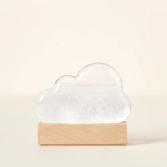 a clear cloud shaped object sitting on top of a wooden block