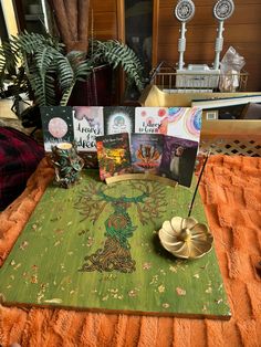 a table topped with lots of books on top of a green rug next to a potted plant