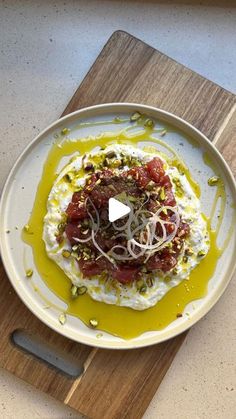 a white plate topped with food on top of a wooden cutting board