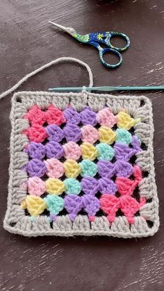 a crocheted square with hearts on it next to a pair of scissors