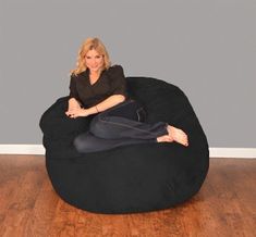 a woman is sitting on a large purple bean bag chair in the middle of a room