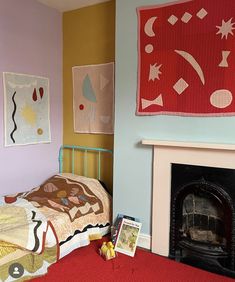 a bed room with a neatly made bed next to a fire place and paintings on the wall