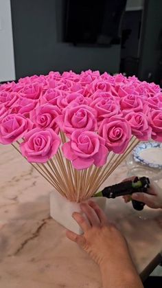 a person holding a bunch of pink roses in front of a table with plates on it