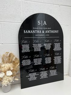 a black and white wedding seating chart on a table with flowers in front of it