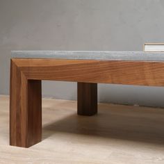 a wooden bench sitting on top of a hard wood floor next to a gray wall