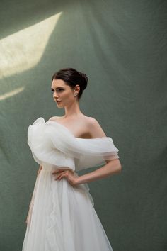 a woman in a white wedding dress posing for the camera with her hands on her hips