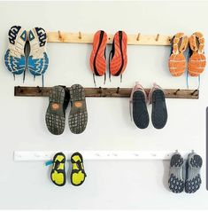 several pairs of shoes are hanging on a wooden rack above a pair of slippers