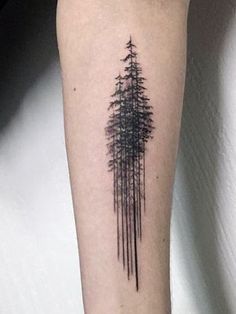 a black and white photo of a forest tattoo on the right arm, with trees in the background