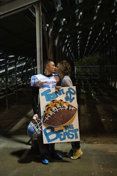 a man and woman standing next to each other holding a sign