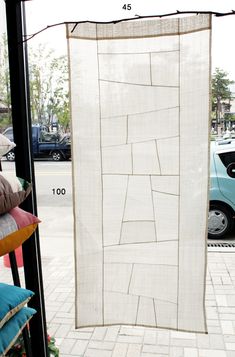 a large white piece of cloth hanging on a pole next to a building with cars parked in the background