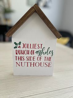 a house shaped sign that says jolliest bunch of wishes this side of the nuthouse