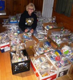 a young boy sitting on top of a pile of boxes filled with toys and other items