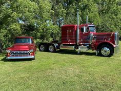 an old red truck is parked in the grass next to a older model pickup truck