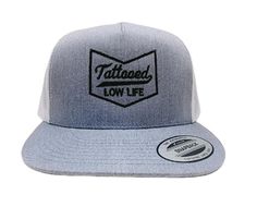 a grey hat with the words tattoo low life on it, and a black patch