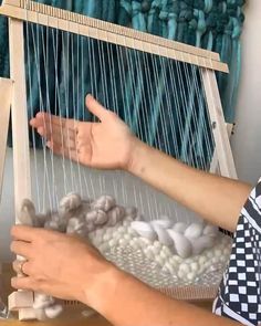 a person is weaving something on a loom with their hands and thumbnails