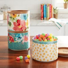 two tins filled with candy sitting on top of a wooden table