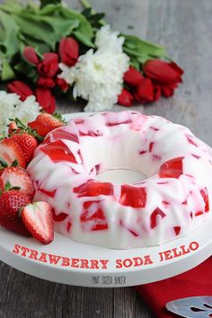 a strawberry soda jello bunt cake on a plate with flowers in the background