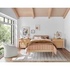 a bed room with a neatly made bed and dressers next to a large window