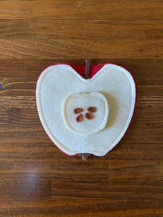 an apple shaped like a heart with two small buttons in the center on a wooden surface