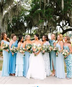 a group of women standing next to each other in front of a tree with flowers