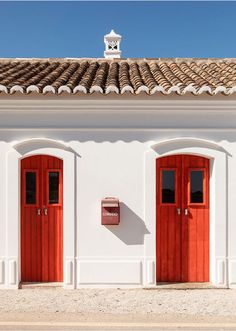 two red doors on the side of a white building