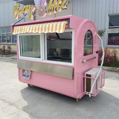 a pink ice cream cart parked in front of a building with an awning over it