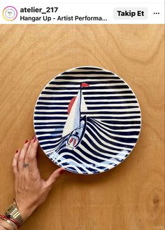 a person holding a plate with a boat painted on the front and side of it