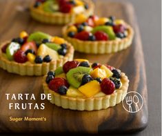 three fruit tarts sitting on top of a wooden cutting board