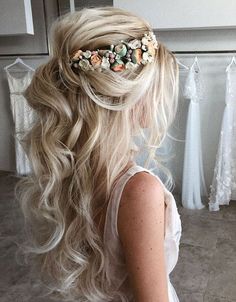 a woman with long blonde hair wearing a flowered headpiece in front of her wedding dress