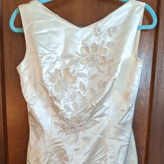 the back of a white dress hanging on a blue hanger in front of a wooden door