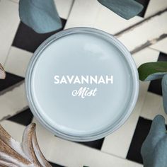 a glass jar with the name savannah mist on it next to some leaves and flowers