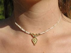 a woman wearing a necklace that has a heart shaped pendant on it's neck