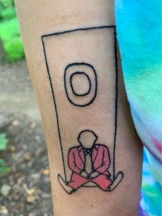 a person with a small tattoo on their arm sitting in front of a toilet paper dispenser