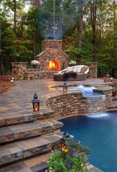 an outdoor fireplace next to a pool in the middle of a wooded area with steps leading up to it