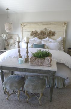 a white bed sitting next to a table with two candles on top of it in a bedroom