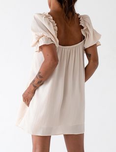 Inspired by beautiful 1950s bed jackets, this nostalgic babydoll mini dress oozes vintage charm. Made with a luxe silk crepe fabric in a dove hue, it's finished with intricate lace, ruffle details, and statement sleeve. Cream Mini Dress With Ruffles And Square Neck, Vintage Cream Mini Dress With Ruffles, Daywear Mini Dress With Ruffles And Square Neck, Vintage Mini Dress With Lace Trim, Feminine Mini Dress With Gathered Neckline For Brunch, Vintage Mini Dress For Wedding, Beige Ruffled Short Sleeve Mini Dress, Cream Vintage Mini Dress, Flowy Cottagecore Dress With Ruffles