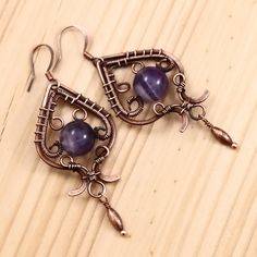 "Handmade vintage earrings; wire wrapped copper earrings with amethyst gemstone; oxidized antiqued copper wire and natural gemstone jewelry 2 1/2\" ( with a hook ) X 15/16\" ( 6.2 X 2.4 cm ) Beautiful amethyst gemstone captured in hand woven antiqued oxidized copper wire. Art Deco inspired. February birthstone. Amethyst is a meditative and calming stone which promotes calm, balance, and peace. It is also used to eliminate impatience. Amethyst is used as beneficial when dealing with legal problem Amethyst Wire Wrapped Drop Earrings, Artisan Handmade Earrings In Copper Wire, Artisan Handmade Earrings With Copper Wire, Artisan Handmade Copper Wire Earrings, Vintage Hand Forged Copper Earrings, Unique Handmade Amethyst Earrings, Bohemian Wire Wrapped Copper Earrings, Artisan Handmade Earrings, Artisan Wire Wrapped Copper Earrings