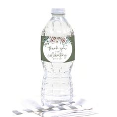 a bottle of water sitting on top of a white tablecloth with a ribbon around it