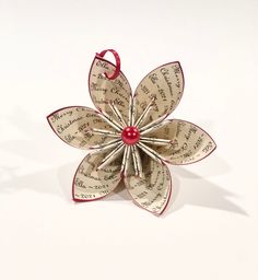 an ornament made out of newspaper with a red bead on the center