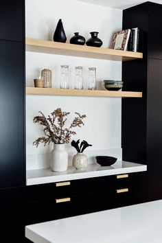 black and white shelves with vases on them in a kitchen area next to a counter